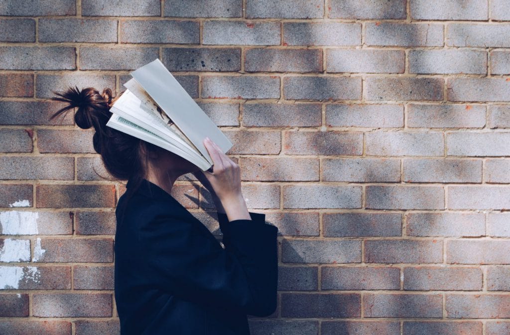 A student covers their face with papers