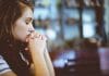 A young woman prays and looks afraid