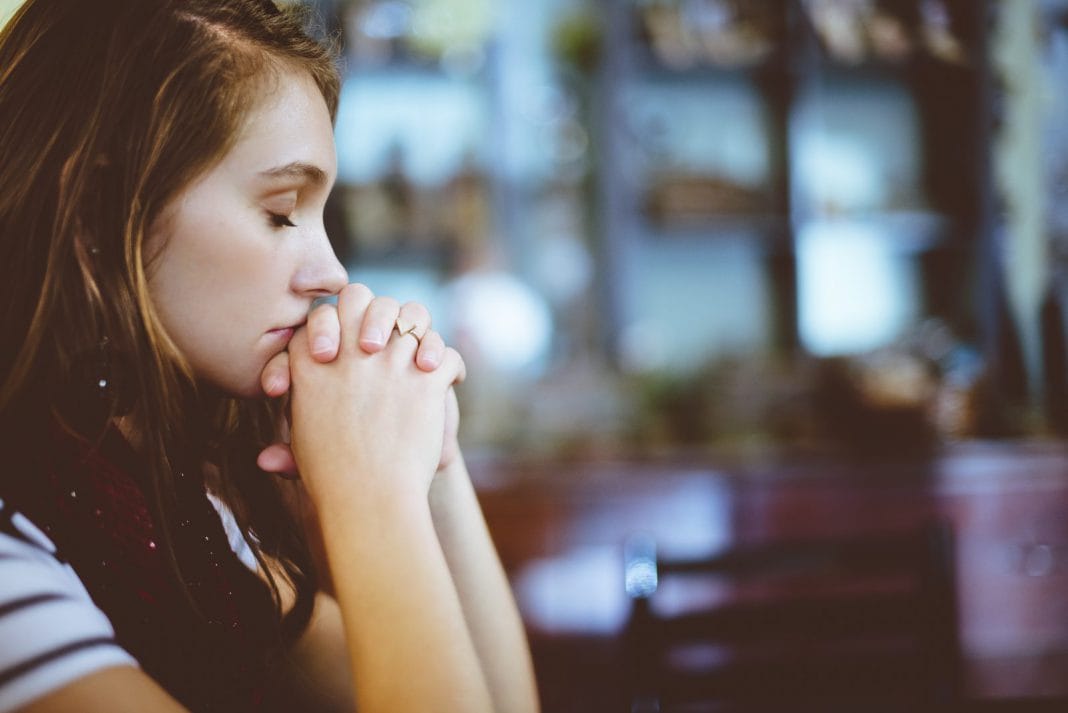 A young woman prays and looks afraid