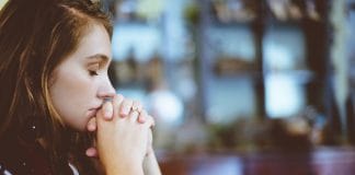 A young woman prays and looks afraid