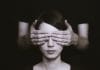 A young woman has her eyes covered by a pair of hands