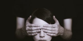 A young woman has her eyes covered by a pair of hands