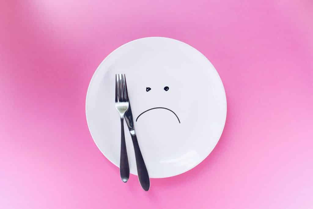 An empty plate with a sad face