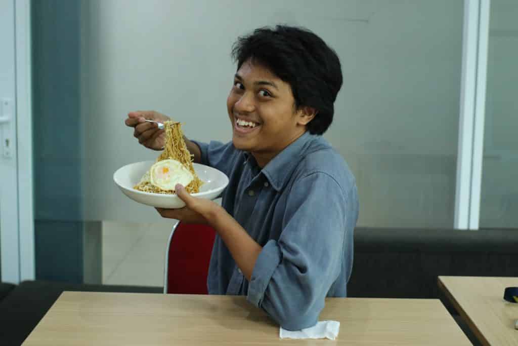 A man smiles while eating food