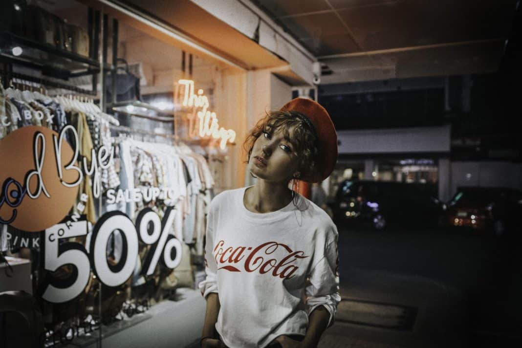 A young woman stands outside a shop that is advertising a sale