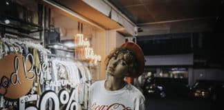 A young woman stands outside a shop that is advertising a sale