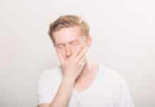 A young man puts his hand across his face with a pained expression