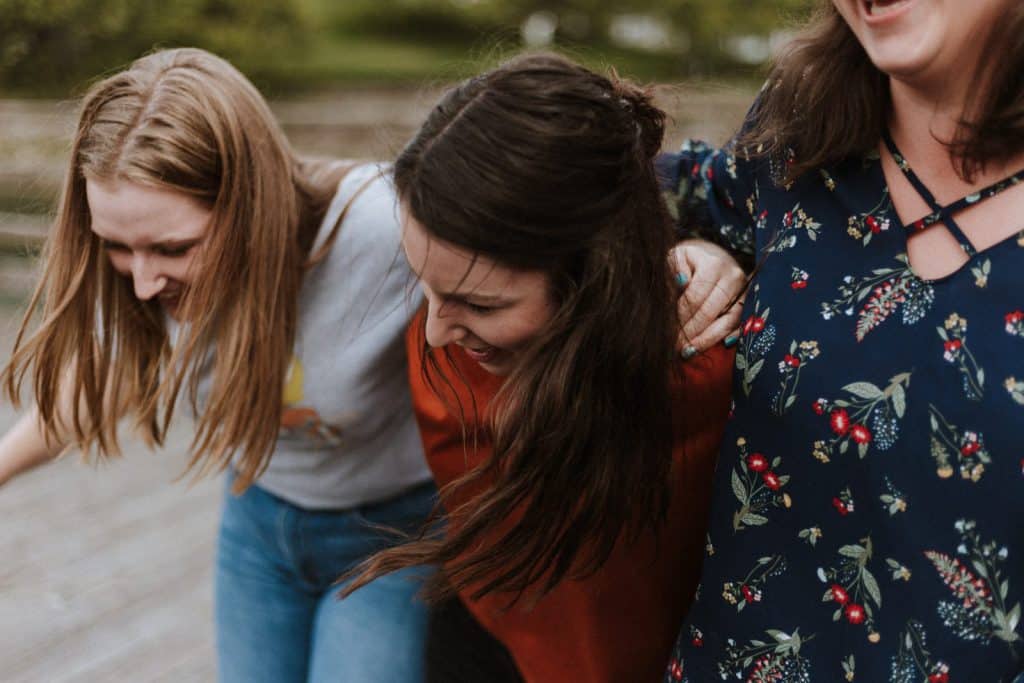 Three girls hug each other while laughing