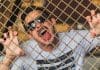 A man sticks his tongue on a metal fence.