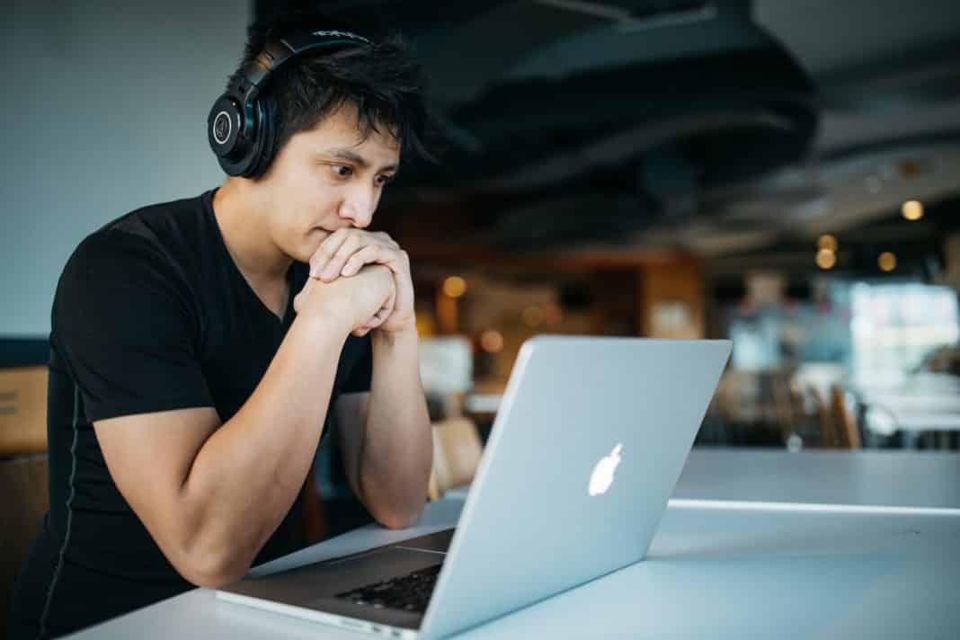 A young man looks at a computer screen.