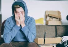 man covering face with both hands while sitting on bench