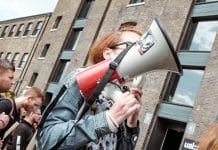 woman holding red and white megaphone standing near building