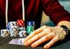 person holding playing cards beside poker chips