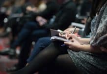 selective focus photography of people sitting on chairs while writing on notebooks