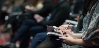 selective focus photography of people sitting on chairs while writing on notebooks