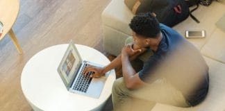 man sitting on couch using MacBook