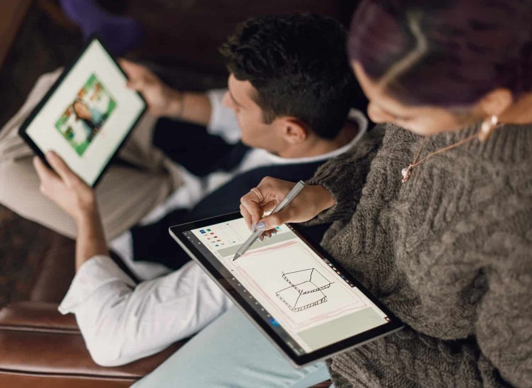 person in gray sweater holding Surface devices