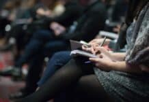 selective focus photography of people sitting on chairs while writing on notebooks