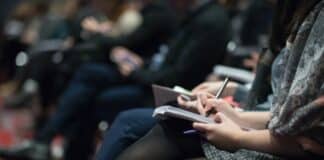 selective focus photography of people sitting on chairs while writing on notebooks