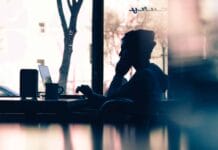 silhouette of a person sitting in front of a laptop