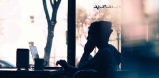 silhouette of a person sitting in front of a laptop
