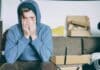 man covering face with both hands while sitting on bench