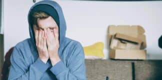 man covering face with both hands while sitting on bench