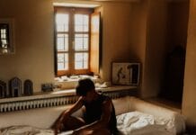 man sitting on bed beside opened window