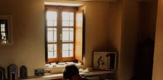 man sitting on bed beside opened window