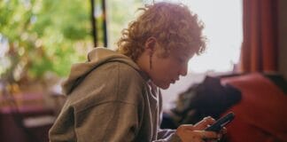 Portrait of a nonbinary autistic person using their mobile phone indoors