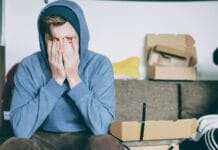 man covering face with both hands while sitting on bench