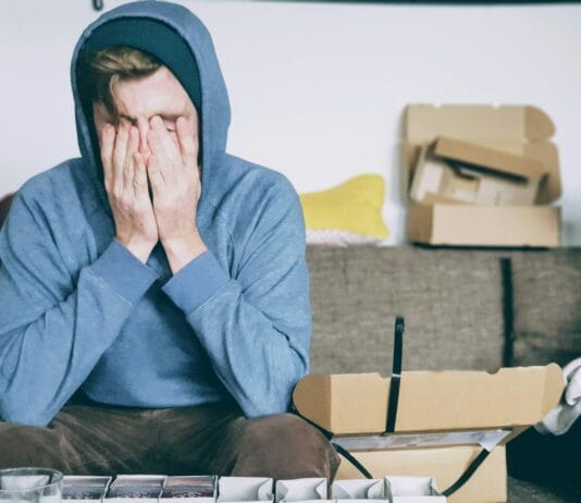 man covering face with both hands while sitting on bench