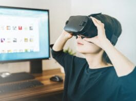 woman using black VR headset beside computer